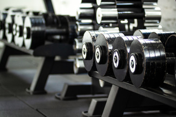 Fototapeta premium Gym equipment. Black dumbbell set. Close up of many metal dumbbells on rack in the gym.
