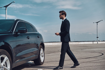 Modern businessman. Full length of handsome young businessman walking to his car
