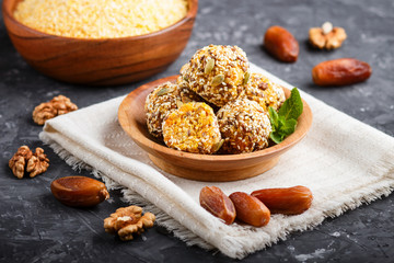 Energy ball cakes with dried apricots, cornflakes, sesame, linen, walnuts and dates on a black concrete  background, side view, close up.