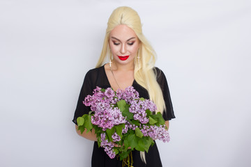 Blonde woman in black evening dress with bouquet of lilac