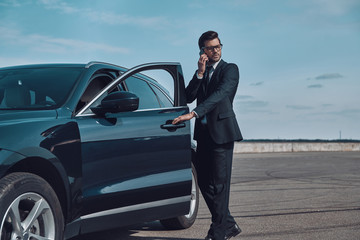 Confident business expert. Full length of handsome young businessman talking on the phone while...