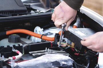 Mechanic checking the car fuse of electric car.
