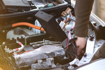 Mechanic checking the car fuse of electric car.