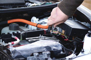 Mechanic checking the car fuse of electric car.