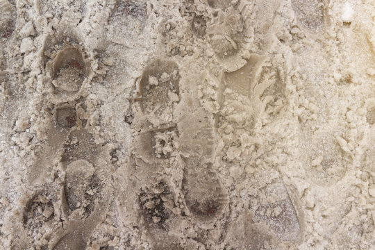 Dirty tracks of snow on asphalt. The footprints of shoes on a dirty snow. Bad ecology, dirty snow.