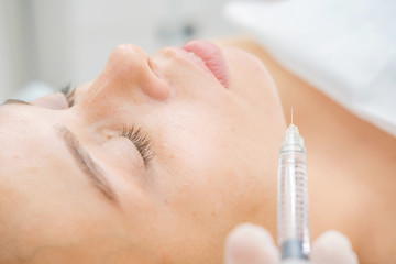 Naklejka premium Cosmetologist making mesotherapy injection. Syringe and needle injecting botox. Female patient, woman is getting botox procedure at beautician. Hardware cosmetology, face rejuvenation. Close up