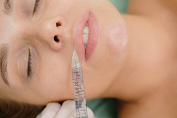 Lips filler injections. Plump lips augmentation. Beauty plastic. Cosmetologist making mesotherapy for woman patient. Syringe and needle, facial cosmetic beauty injection.