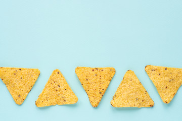 Nachos chips laid out on a blue background. Flat lay, copy space. 