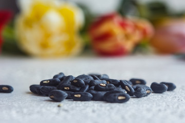 A heap of dried black haricot seeds close-up on a white table background. bean sowing season. close up top view copy space