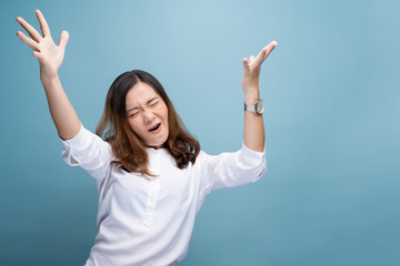 Happy woman make winning gesture isolated over blue background