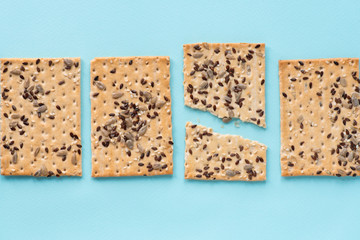 Crispbread with sunflower, flax and sesame seeds on a blue background. Top view, flat lay