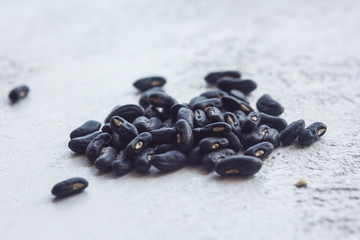 A heap of dried black haricot seeds close-up on a white table background. bean sowing season. close up top view copy space
