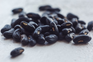 A heap of dried black haricot seeds close-up on a white table background. bean sowing season. close up top view copy space