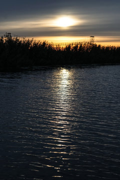 Sunset on the river, lake. The reflection of the sun in the water as in a mirror. Landscape background. Stock photo