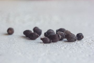 A heap of dried black flower seeds close-up on a white table background. planting season. close up top view copy space