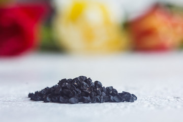 A heap of dried black flower seeds close-up on a white table background. planting season. close up...