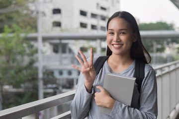 portrait of happy smiling asian woman college student pointing up 4 fingers, four points pose;...