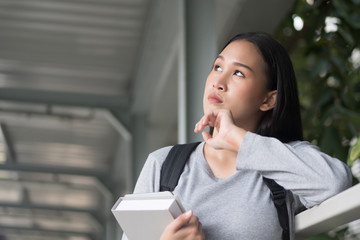 portrait of thoughtful asian woman college student thinking and looking up at possible education...