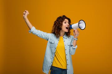 curly redhead woman screaming in megaphone and gesturing on orange