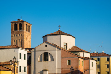 Fototapeta na wymiar Church Santa Andrea with tower en colorful houses in Chioggia, Italy