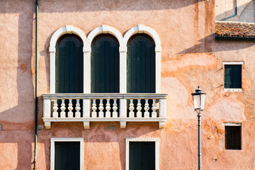 Fototapeta na wymiar detail of orange house with balcony and shutters in Chioggia, Italy