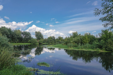 Obraz premium Beautiful summer landscape with pretty river and colorful trees. View of the sky with beautiful clouds. Stock photo