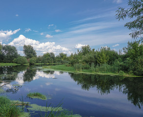 Fototapeta na wymiar Beautiful summer landscape with pretty river and colorful trees. View of the sky with beautiful clouds. Stock photo