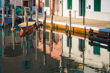 Fototapeta na wymiar houses and red boat, reflection in canal of Chioggia, Italy