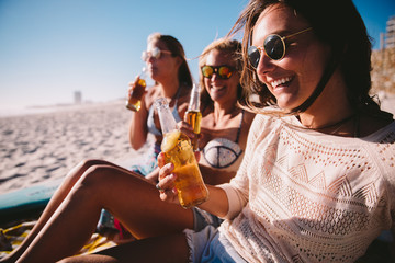friends cheering with beer at the beach celebrating