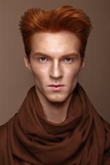 Young man with red hair and creative make up and hair.