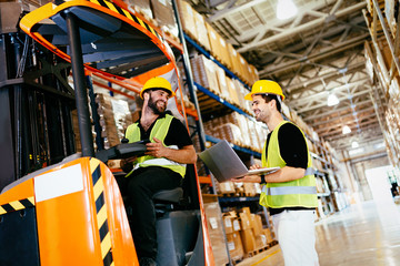 Warehouse workers working together with forklift loader © NDABCREATIVITY