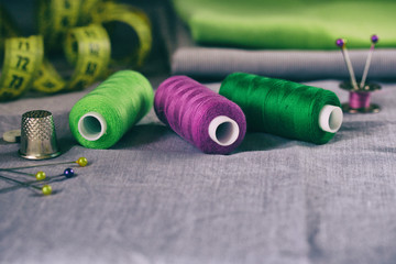 Sewing accessories in green and purple on a gray fabric background