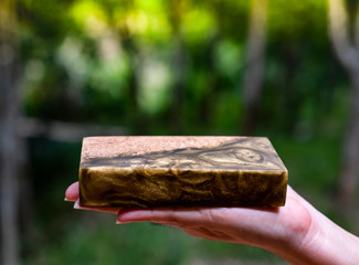 Hand holding casting epoxy resin Stabilizing burl Afzelia wood color abstract art background for blanks