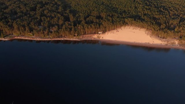 Aerial White Dune on the river Lielupe in Varnukrogs - Golden Hour sunset top view from above - Drone shot with evergreen pine seaside forest visible in the background - Balta Kapa