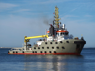 Ocean going anchor handling & towing vessel approaching ships berth at port facilities.