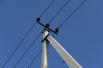 Electric post with blue sky background.