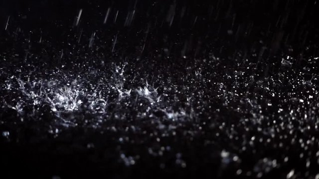 Drops of water falling on a dark colored floor
