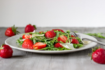 Salad of strawberries, arugula and cheese on a grey background. Dietary food.