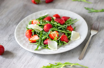 Salad of strawberries, arugula and cheese on a grey background. Dietary food.