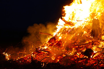 Large bonfire, burning and glowing with soft flames, sparkles flying agains the dark sky. Glowing...