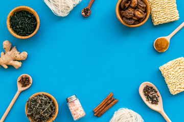 Chinese and Japanese food cooking with ginger, spices and noodles frame on blue background top view mockup