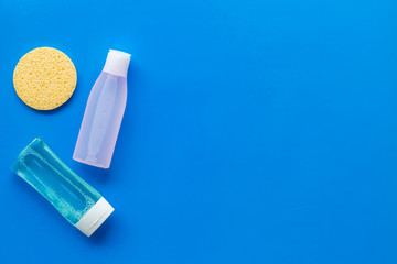 skin care cosmetics with facial tonic, mycelial water and sponge on blue background top view mockup