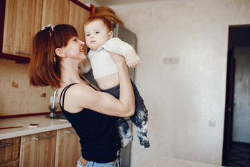 A young and beautiful mom playing with his little son at home