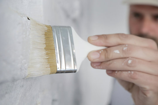 Painting A White Brick Wall With A Paint Brush