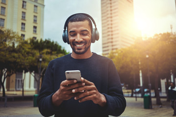 Young man looking at smartphone with headphone on his head