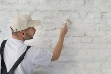 Painting a white brick wall with a paint brush