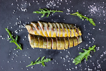 Herring and mackerel on a dark background with onions and arugula