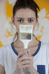 Portrait of a young female painter with a brush, renovating house and painting walls concept