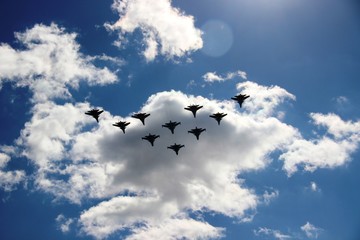 A group of ten aircraft in a blue sky with white clouds. Ten planes in a blue sky with clouds on a Sunny day. selective focus