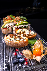 Delicious Italian antipasti bruschetta on black background. Close-up.